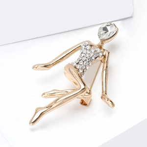 Dettaglio macro della spilla ballerina dorata con strass bianchi e grande gemma sfaccettata