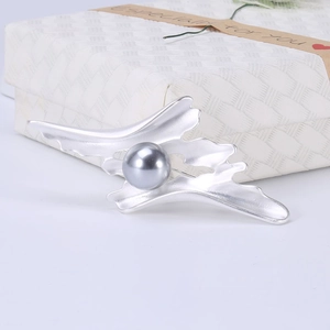 Détail macro d'une broche abstraite en argent mat avec une perle grise centrale