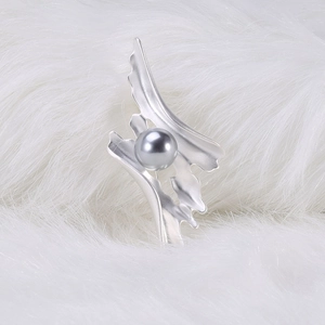 Macro d'une broche argentée avec une perle grise sur un fond en fausse fourrure