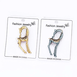 Detail view of two giraffe-shaped alloy brooches in gold and vintage blue-grey finishes