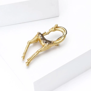 Detailed view of a matte gold giraffe brooch with brown spots on a white platform
