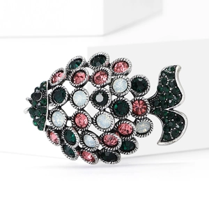 Elegant hollow fish brooch in vintage silver with colorful rhinestones on a white pedestal