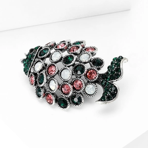 Detail view of fish brooch with green, pink, and white rhinestones in vintage silver setting