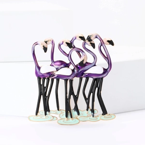 Detail van emaille flamingo broche met paarse accenten op een gouden metalen basis