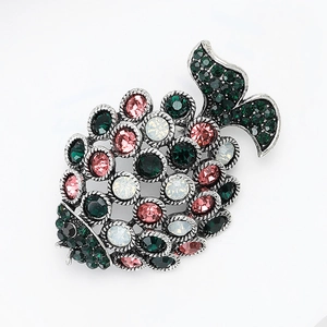 Detailed macro view of hollow silver fish brooch with pink and green rhinestones