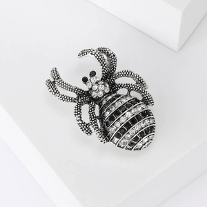 Detailed close-up of a silver spider brooch with sparkling rhinestones and textured metal