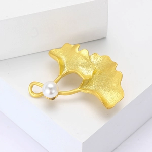 Élégante broche feuille de ginkgo dorée avec perle blanche sur surface en métal mat