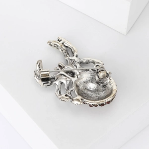 Macro detail of octopus brooch back showing secure silver safety pin and red crystals