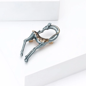 Detail of deer brooch with blue enamel and gold spots on minimalist white stone
