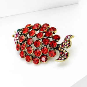 Detailed macro view of vintage fish brooch with red rhinestones and golden metal texture