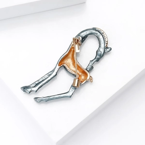 Detail view of silver-blue alloy horse brooch with golden saddle and back pin