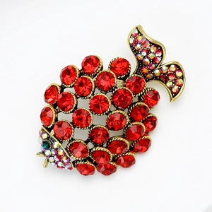 Close-up of vintage fish brooch with red faceted rhinestones and antique gold finish