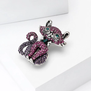 Detailed macro view of purple crystal cat brooch with emerald eyes on white geometry