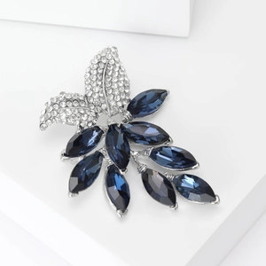 Detail of elegant leaf brooch with dark blue marquise gems and white rhinestones