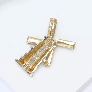 Detailed back view of golden windmill brooch with textured metal finish and safety pin clasp