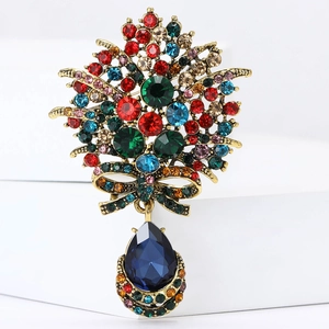 Détail d'une broche fleur dorée vintage avec strass colorés et pierre poire bleue