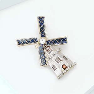 Detailed close-up of a golden windmill brooch with blue enamel blades and crystal accents