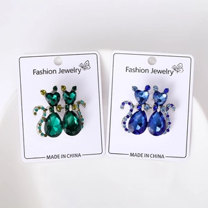 Close-up of green and blue crystal cat brooches with bowknot and rhinestone details