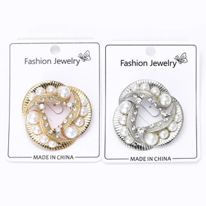 Detail of gold and silver pearl brooches with twisted swirl design and crystal accents