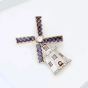 Detail of purple enamel windmill brooch with white rhinestones on golden metal base