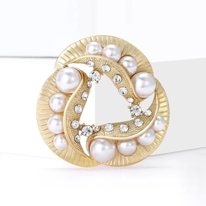 Elegant gold brooch with pearls and crystals on a geometric white display stand