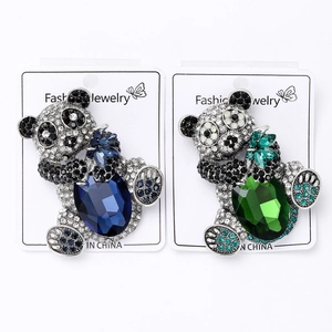 Detail of panda brooches with large blue and green gemstones on jewelry display cards