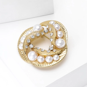 Close-up of golden pearl brooch with sparkling rhinestones on minimalist white background