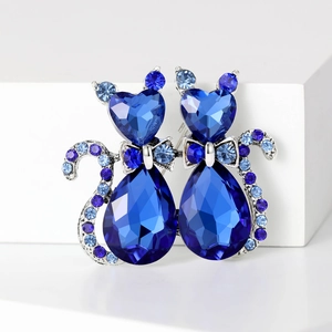 Macro shot of twin cat brooches with dark blue crystals and silver bow details