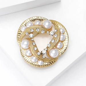 Detailed macro view of a vintage gold brooch featuring white pearls and sparkling rhinestones