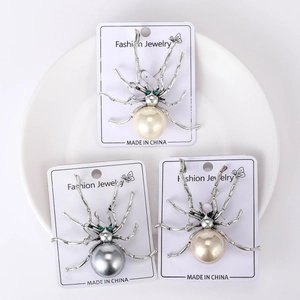 Nahaufnahme einer Vintage Spinne Brosche mit weißen und grauen Perlen auf Silber