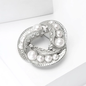 Detailed view of silver spiral brooch with white pearls and sparkling rhinestones