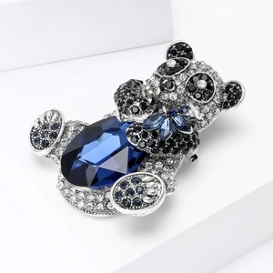 Macro detail of silver panda brooch featuring a large blue oval gemstone and sparkling crystals