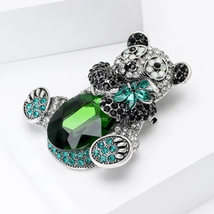 Macro detail of luxury panda brooch with green gemstone and sparkling crystals