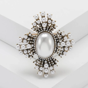 Baroque style gold-tone brooch featuring a large center pearl and starburst sunburst design