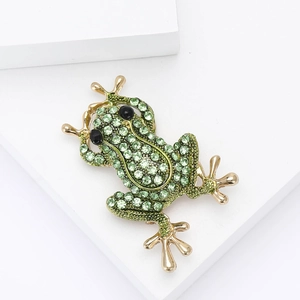 Détail de la broche grenouille en strass verts avec finition dorée élégante