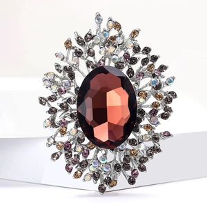 Detailed macro of vintage crystal brooch featuring brown oval stone and intricate crystal frame