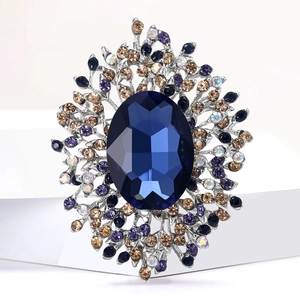 Elegant silver brooch with deep blue oval stone and multi-color crystals on white stand