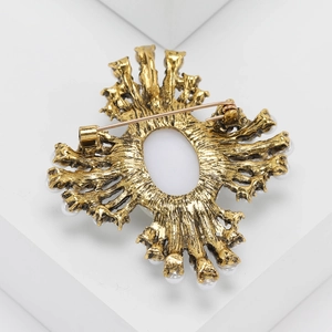 Detail view of vintage gold brooch back featuring a sturdy pin clasp and pearl edges