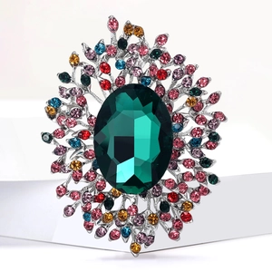 Macro shot of luxury brooch with emerald crystal and colorful rhinestone floral detail