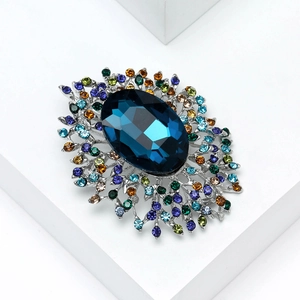 Macro detail of luxury crystal brooch with deep blue center stone and multi-color rhinestones