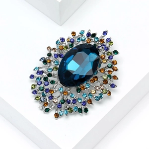 Detail of luxury alloy brooch featuring a large blue crystal and colorful rhinestones