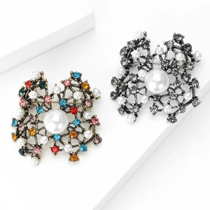 Vintage flower brooches with colorful rhinestones and elegant pearls on white stand