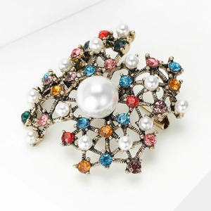 Detail shot showing the vintage pearl brooch with colorful rhinestones on a gold base