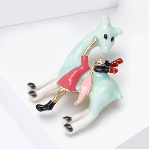 Détail d'une broche en émail montrant une fille avec des girafes sur fond blanc