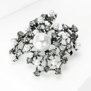 Detail shot of vintage silver brooch with rhinestones and white round pearls
