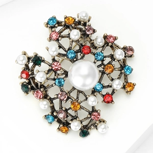 Macro shot of vintage brooch with colorful rhinestones and white pearls on gold alloy