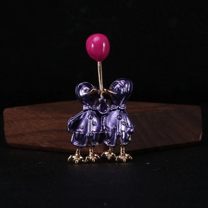 Detailed macro view of enamel duck couple brooch with a pink balloon in high-quality finish