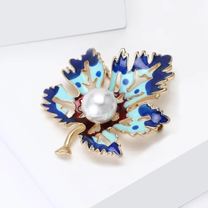 Détail de la broche feuille avec glaçage émail bleu et une grande perle blanche au centre