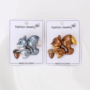 Vue détaillée de deux broches écureuil en émail avec glands sur cartes de bijoux