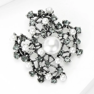 Close-up of vintage snowflake brooch with large pearl and grey rhinestones detail